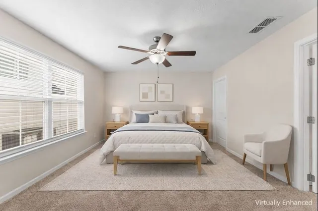 a bedroom with a large bed and a chandelier fan