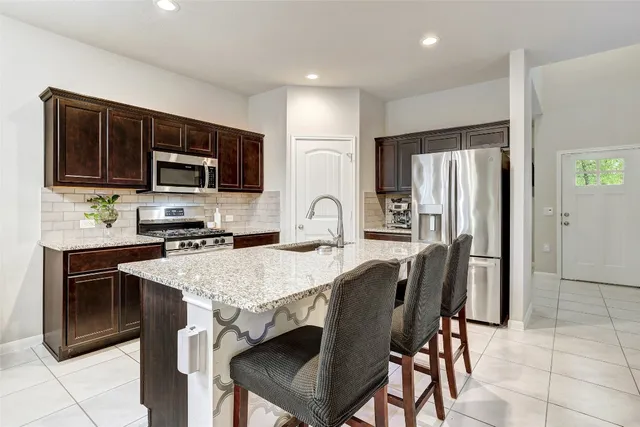 a kitchen with stainless steel appliances granite countertop a sink stove and refrigerator