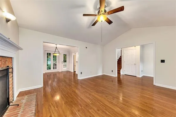 a view of an empty room with window and wooden floor