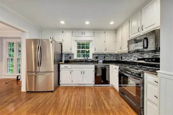 a kitchen with granite countertop a refrigerator stove top oven and sink