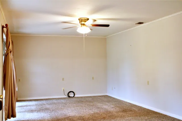 a view of an empty room with window and chandelier fan