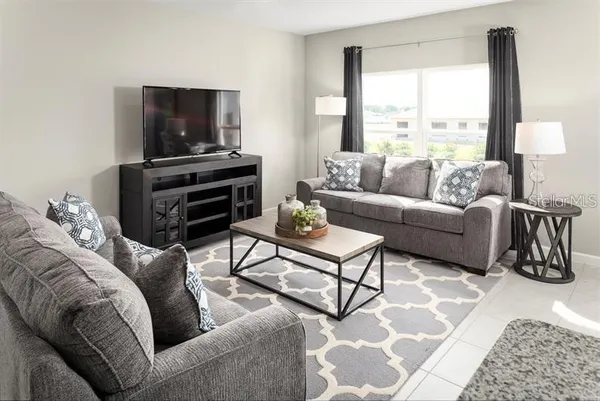 a living room with furniture a flat screen tv and a window