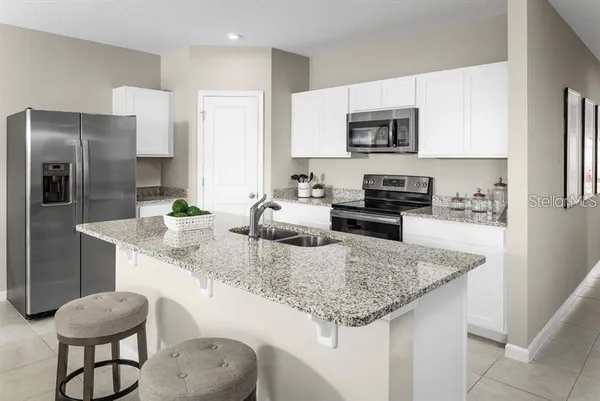 a kitchen with stainless steel appliances granite countertop a sink refrigerator and microwave