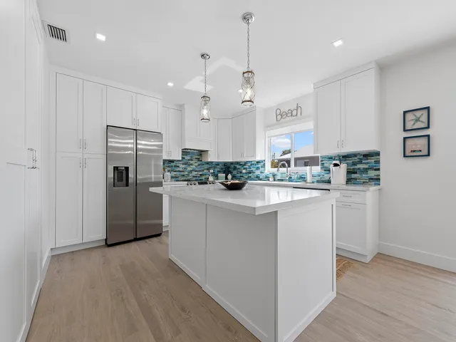 a kitchen with kitchen island white cabinets and refrigerator