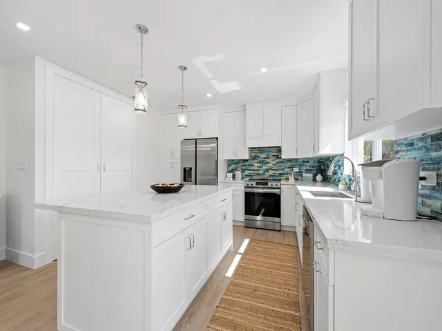 a kitchen with kitchen island a counter top space a sink stainless steel appliances and cabinets