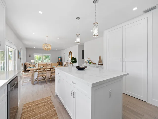 a kitchen with a sink dishwasher a dining table and chairs with wooden floor