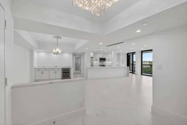 an empty room with chandelier fan and windows
