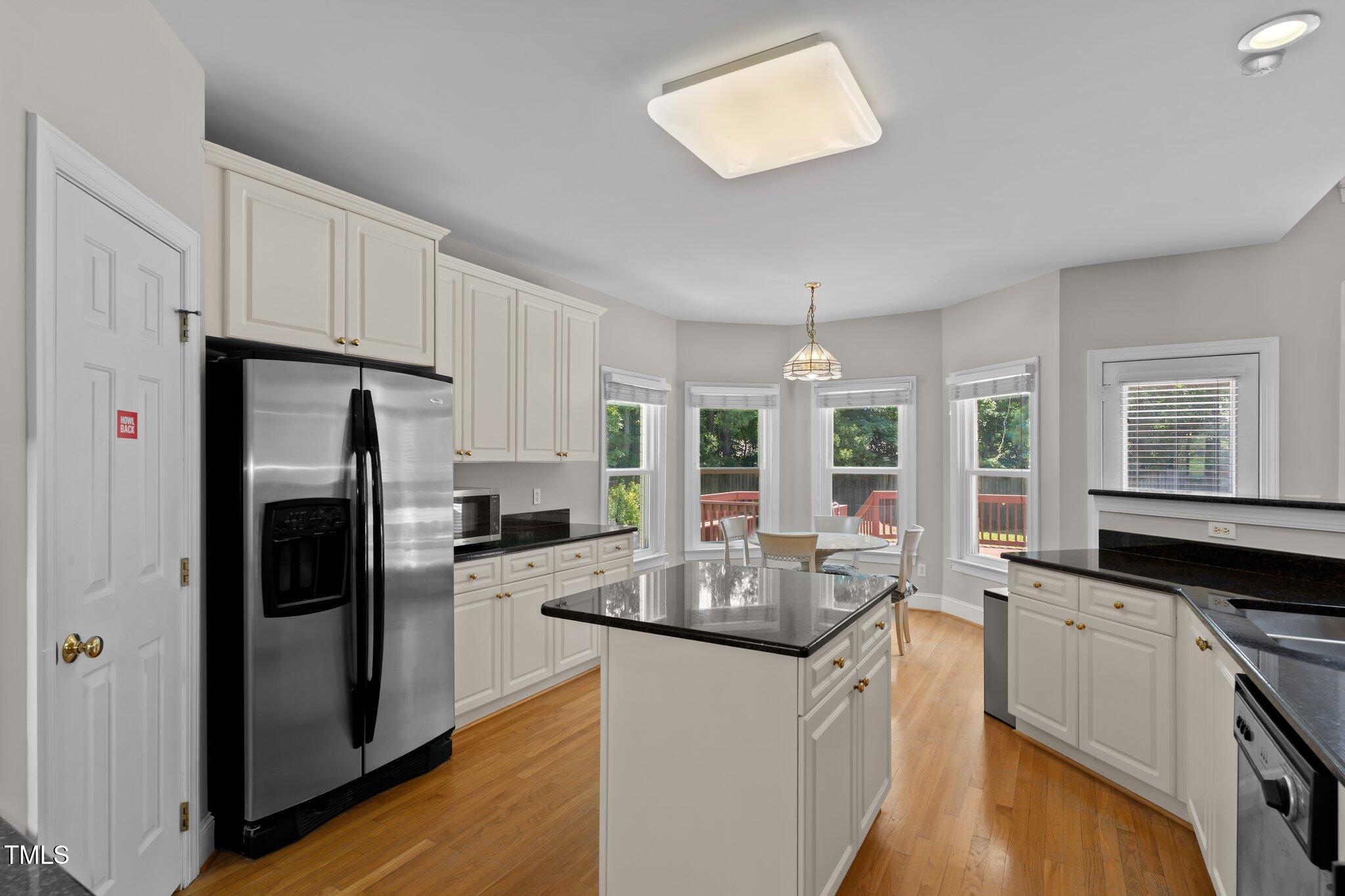 3556 Iris Street Wilmington, NC 28409 - Photo 13 of 52 a kitchen with granite countertop a refrigerator a sink a stove and white cabinets with wooden floor