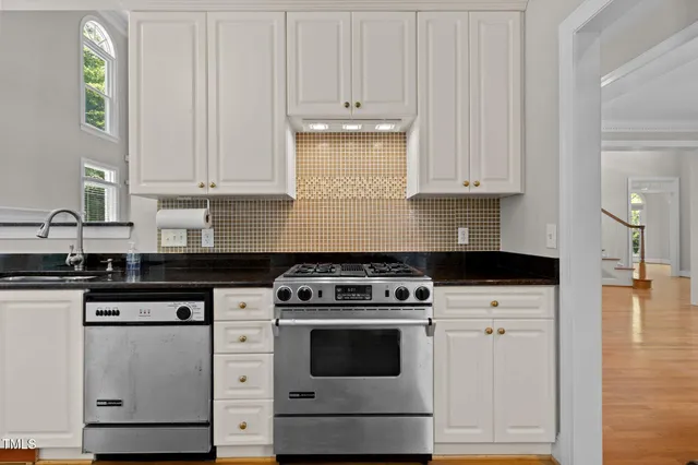 a kitchen with stainless steel appliances granite countertop a sink a stove and a wooden floors