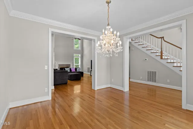 a view of an empty room with wooden floor and a chandelier