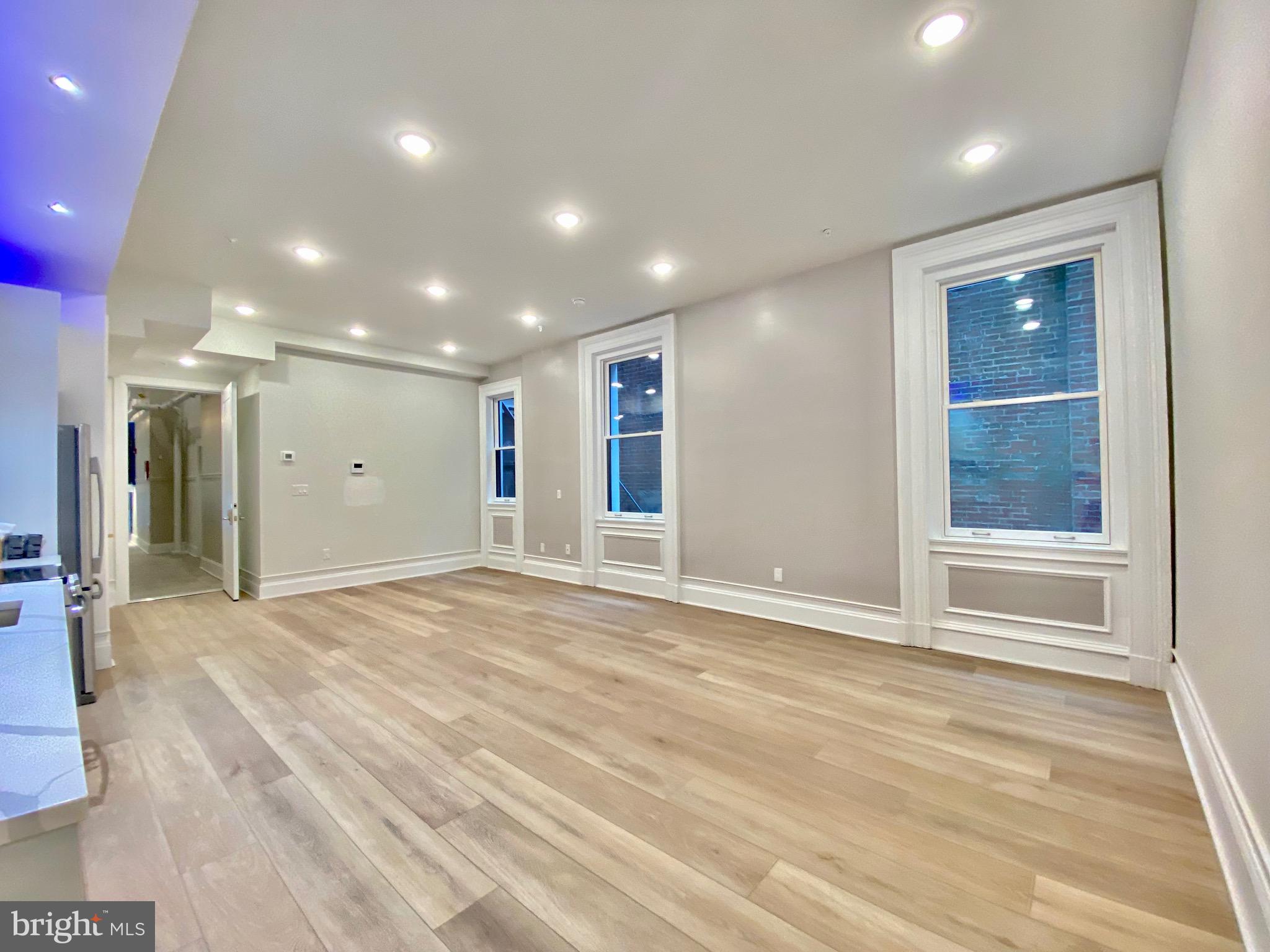 1824 Chestnut Street, Unit 1R Philadelphia, PA 19103 - Photo 5 of 12 a view of an empty room with wooden floor and windows