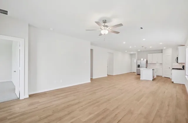a view of a big room with wooden floor and a ceiling fan