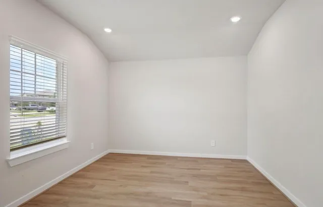 a view of an empty room with wooden floor and a window