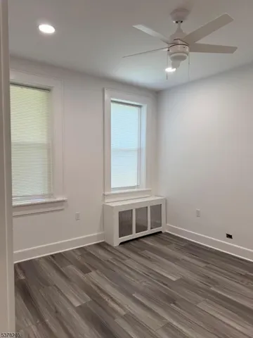 an empty room with wooden floor fan and windows