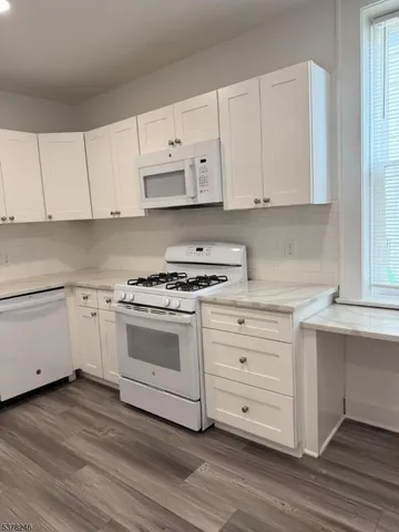a kitchen with granite countertop white cabinets and white appliances