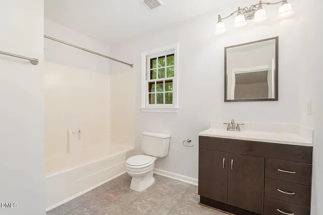 a bathroom with a toilet a sink a mirror a bathtub and vanity