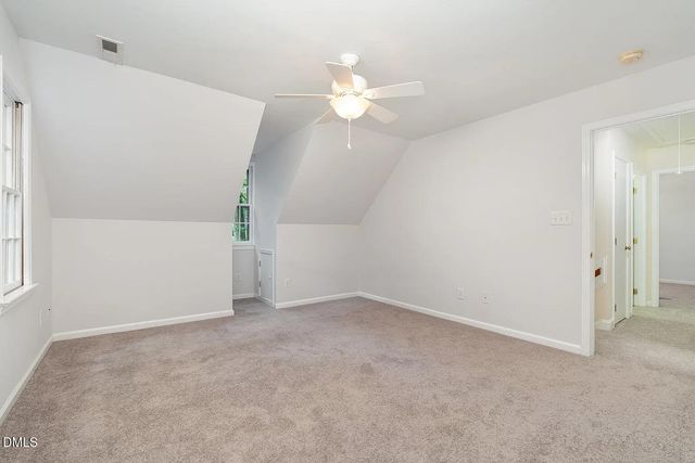 an empty room with a chandelier fan and windows