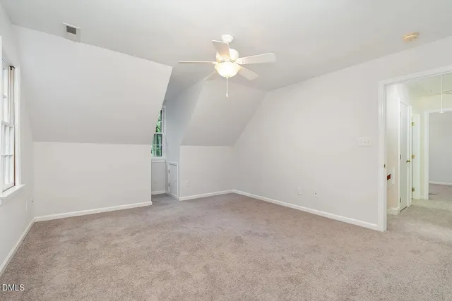 an empty room with a chandelier fan and windows