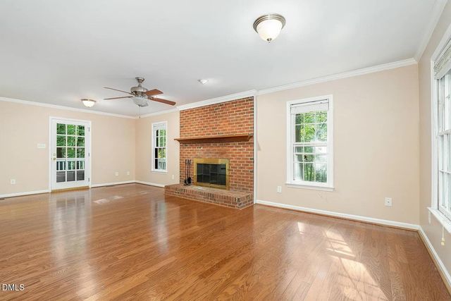 an empty room with wooden floor fireplace and windows