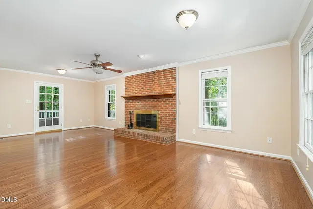 an empty room with wooden floor fireplace and windows
