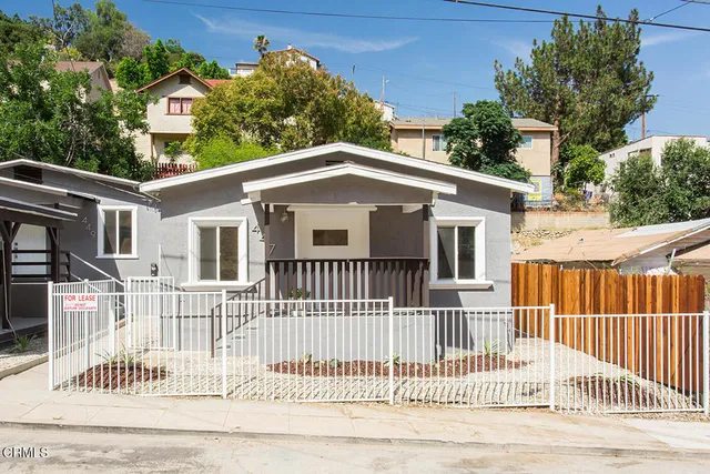a white house that has a small garden and wooden fence