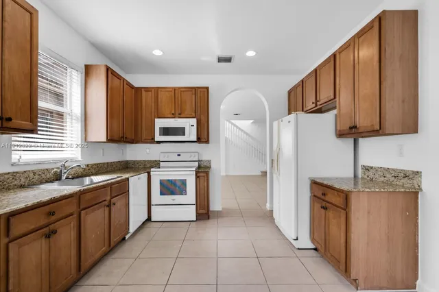 a kitchen with stainless steel appliances granite countertop a refrigerator a stove top oven a sink and dishwasher