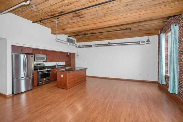 a view of a kitchen with wooden floor and stainless steel appliances