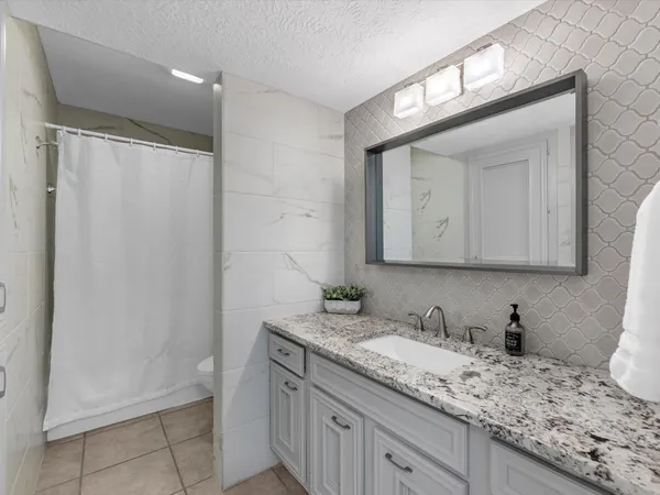a bathroom with a granite countertop sink a mirror and a shower