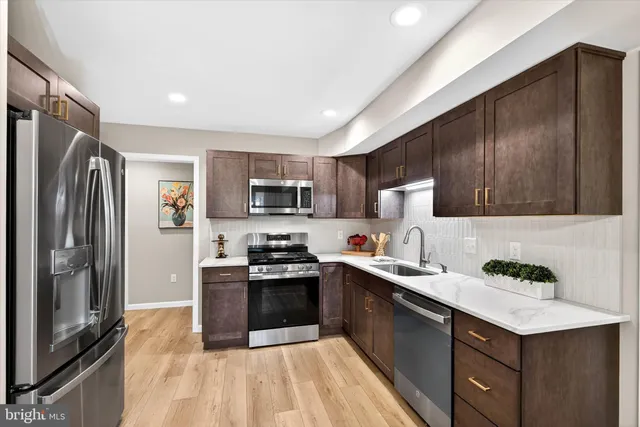 a kitchen with stainless steel appliances granite countertop a sink stove refrigerator and cabinets