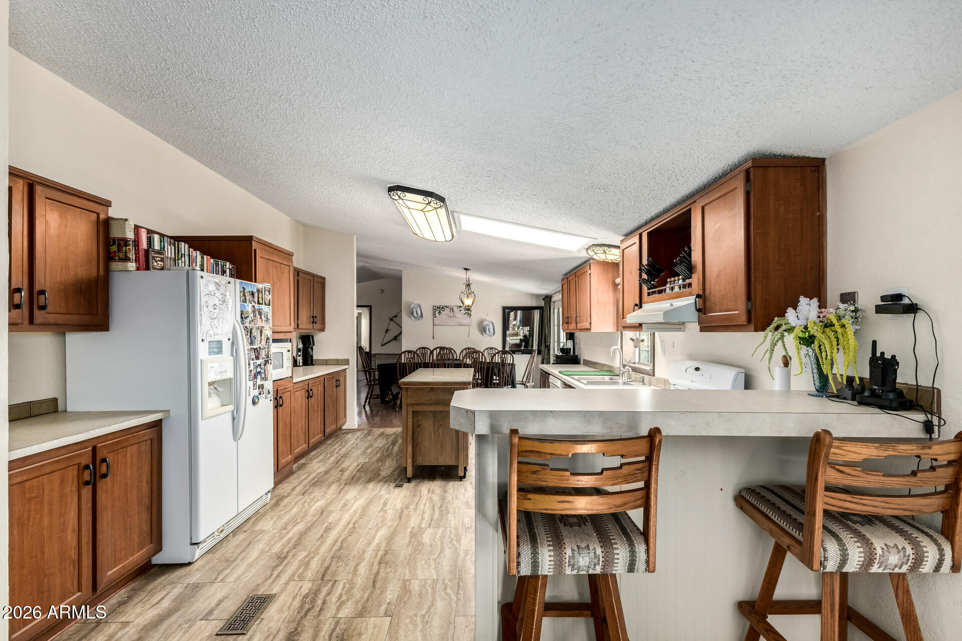 9987 North Geronimo Drive Casa Grande, AZ 85122 - Photo 16 of 53 a kitchen with stainless steel appliances kitchen island granite countertop a refrigerator a stove top oven a sink dishwasher and white cabinets with wooden floor