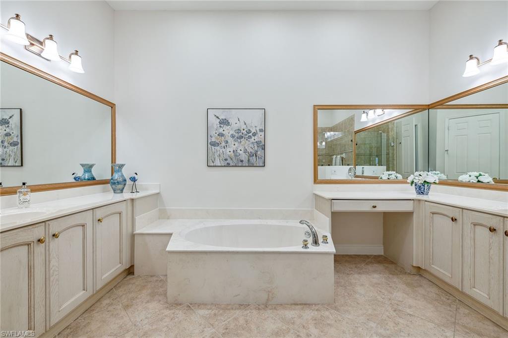 9259 Museo Circle, Unit 201 Naples, FL 34114 - Photo 15 of 50 a bathroom with a tub a sink and mirror