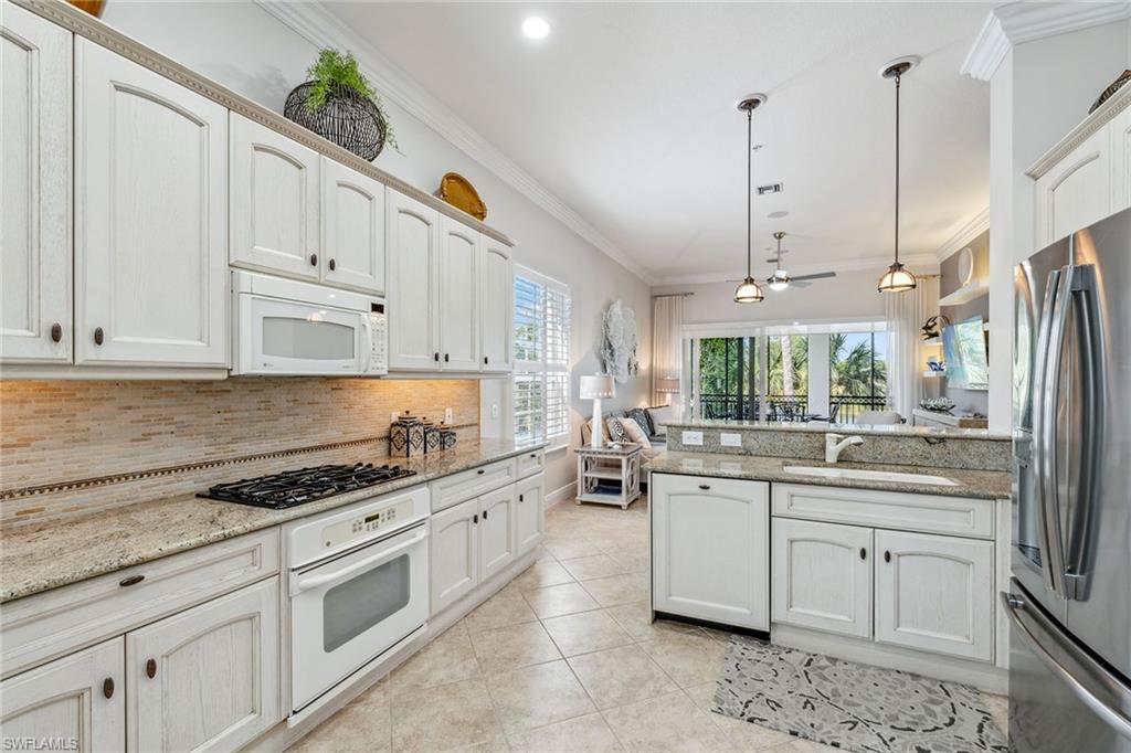 9259 Museo Circle, Unit 201 Naples, FL 34114 - Photo 5 of 50 a kitchen with stainless steel appliances a sink a stove a refrigerator and cabinets