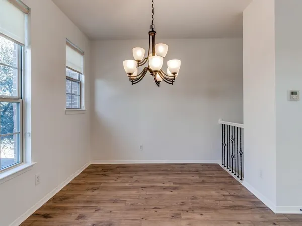 a view of a room with wooden floor chandelier and windows