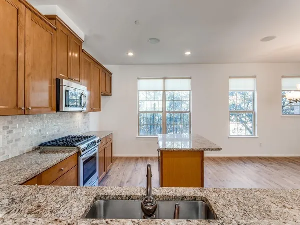 a kitchen with stainless steel appliances granite countertop a stove a sink and a microwave