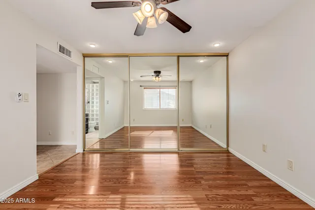 a view of empty room with wooden floor and fan