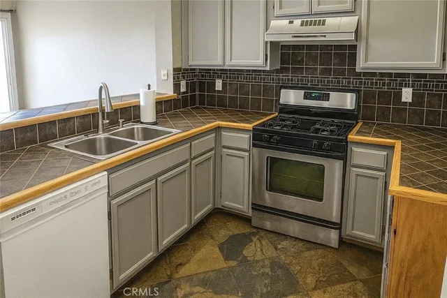 a kitchen with granite countertop a sink a stove and cabinets