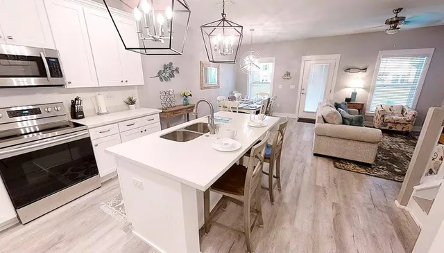 a open kitchen with stainless steel appliances a stove a sink dishwasher a dining table and chairs with wooden floor