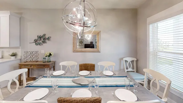 a dining room with wooden floor a chandelier a glass table and chairs