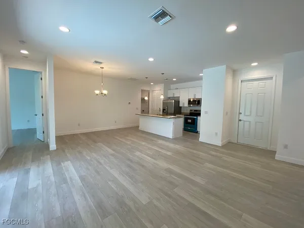 an empty room with wooden floor and an entrance to ceiling window