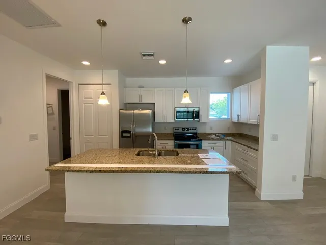 a kitchen with kitchen island granite countertop stainless steel appliances a sink refrigerator and microwave