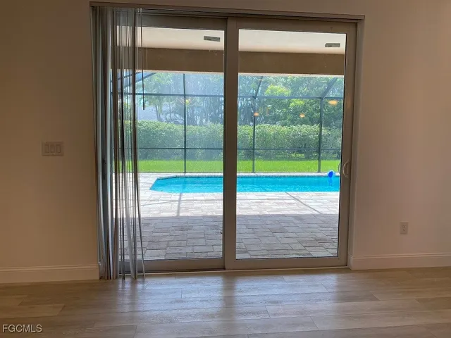 a view of empty room with wooden floor and floor to ceiling window