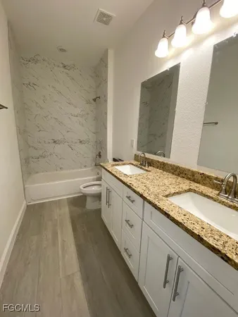 a bathroom with a granite countertop sink a toilet and bathtub