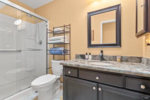a bathroom with a granite countertop sink toilet mirror and shower