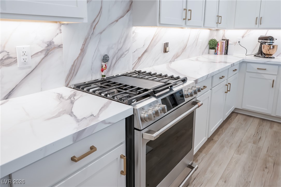 3018 Bounding Home Road North Las Vegas, NV 89086 - Photo 18 of 43 Kitchen featuring stainless steel gas range, light stone counters, and white cabinets