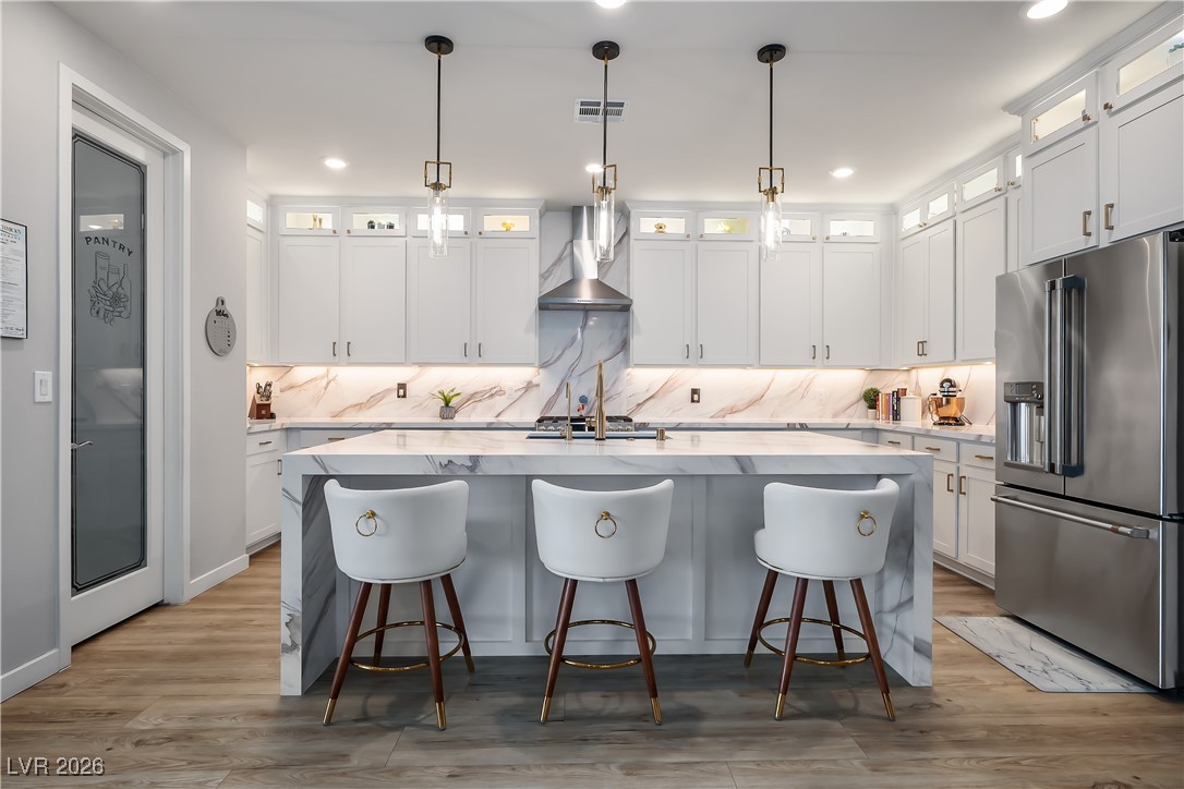 3018 Bounding Home Road North Las Vegas, NV 89086 - Photo 3 of 43 Kitchen with high end refrigerator, light stone countertops, a breakfast bar, white cabinetry, and glass insert cabinets