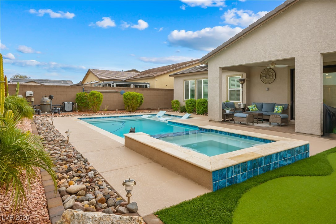 3018 Bounding Home Road North Las Vegas, NV 89086 - Photo 36 of 43 View of pool featuring a patio area, a pool with connected hot tub, a fenced backyard, and outdoor lounge area