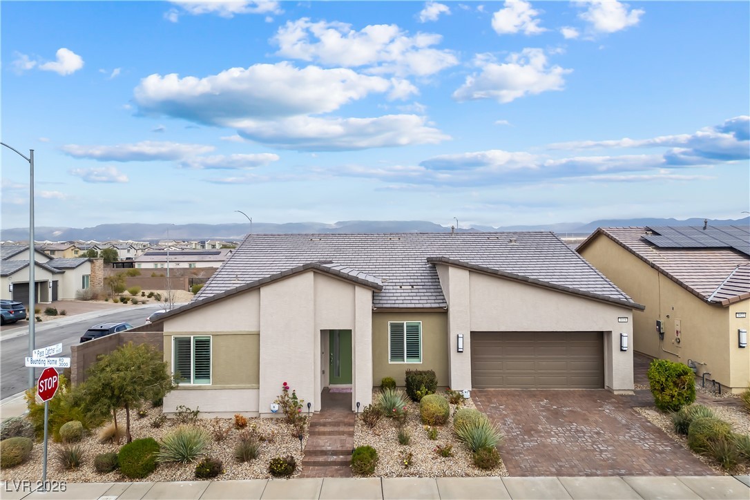 3018 Bounding Home Road North Las Vegas, NV 89086 - Photo 4 of 43 View of front facade featuring stucco siding, an attached garage, a tiled roof, decorative driveway, and a mountain view