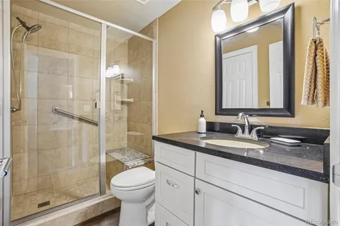a bathroom with a granite countertop sink toilet and shower