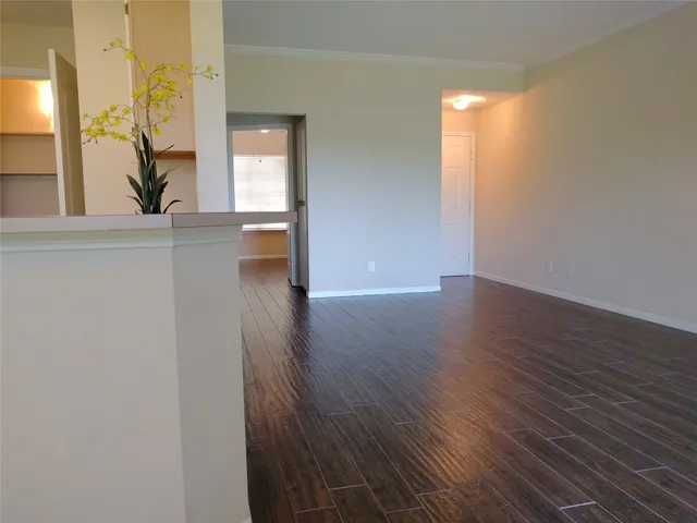 a view of a hallway with wooden floor and a bathroom