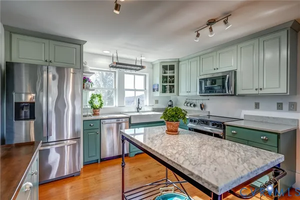 a kitchen with stainless steel appliances granite countertop a stove a sink dishwasher a dining table and chairs with wooden floor